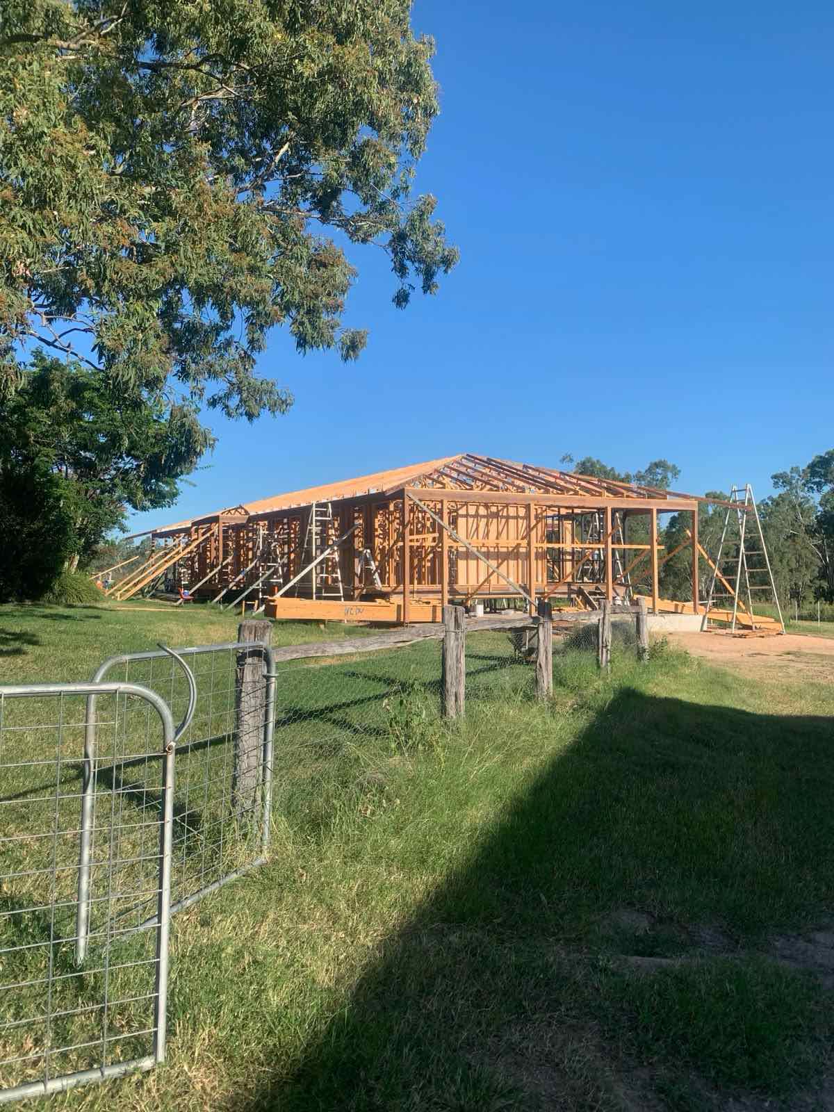 House frame standing on its slab with a carpenter working at roof height