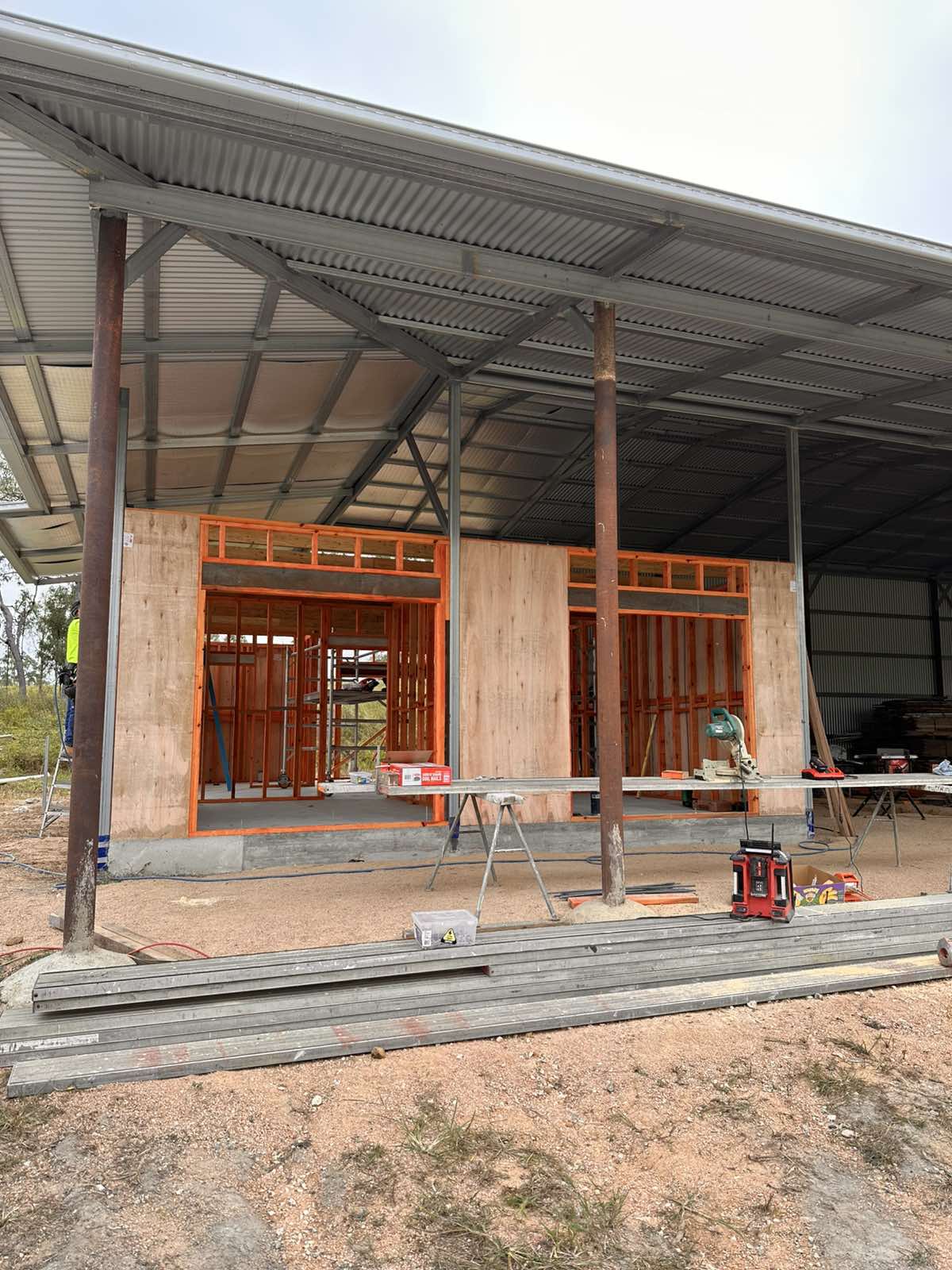Timber-framed new build with corrugated iron roof under a clear blue sky