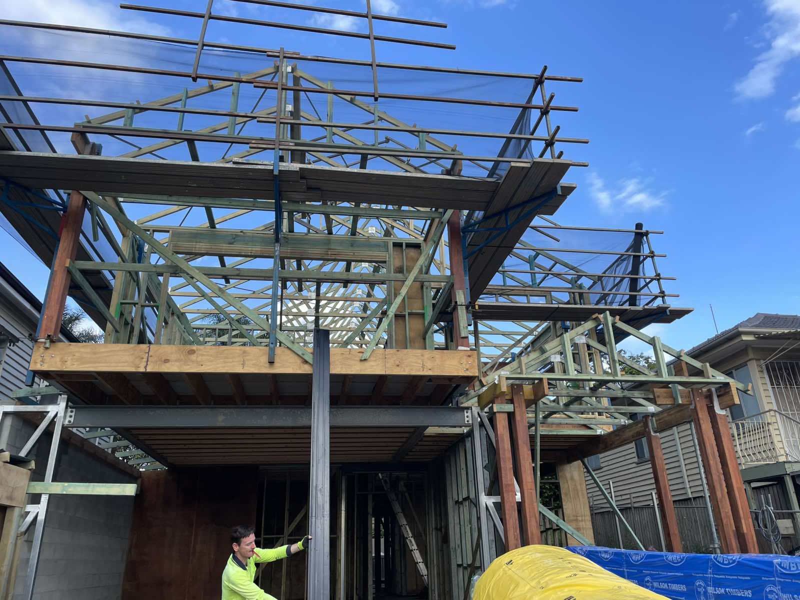 Timber roof trusses being installed against a clear blue sky