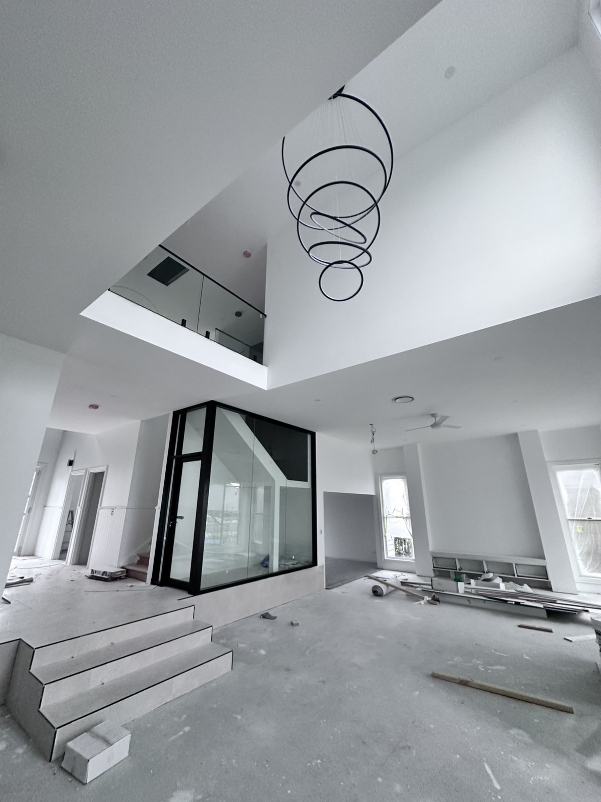 Double-height stairwell void with statement pendant light and glass balustrade